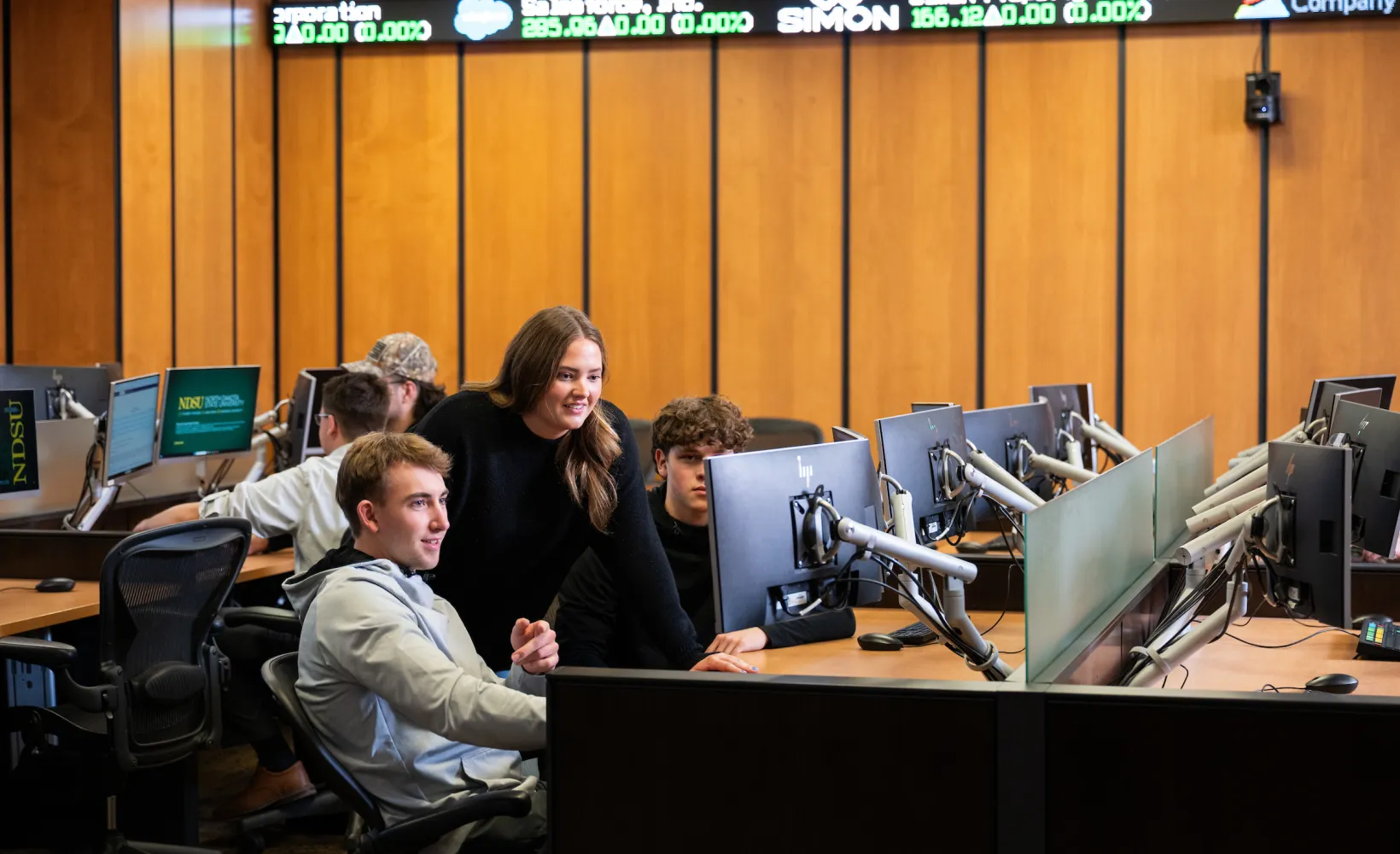 business students gathered around a computer in the trading room