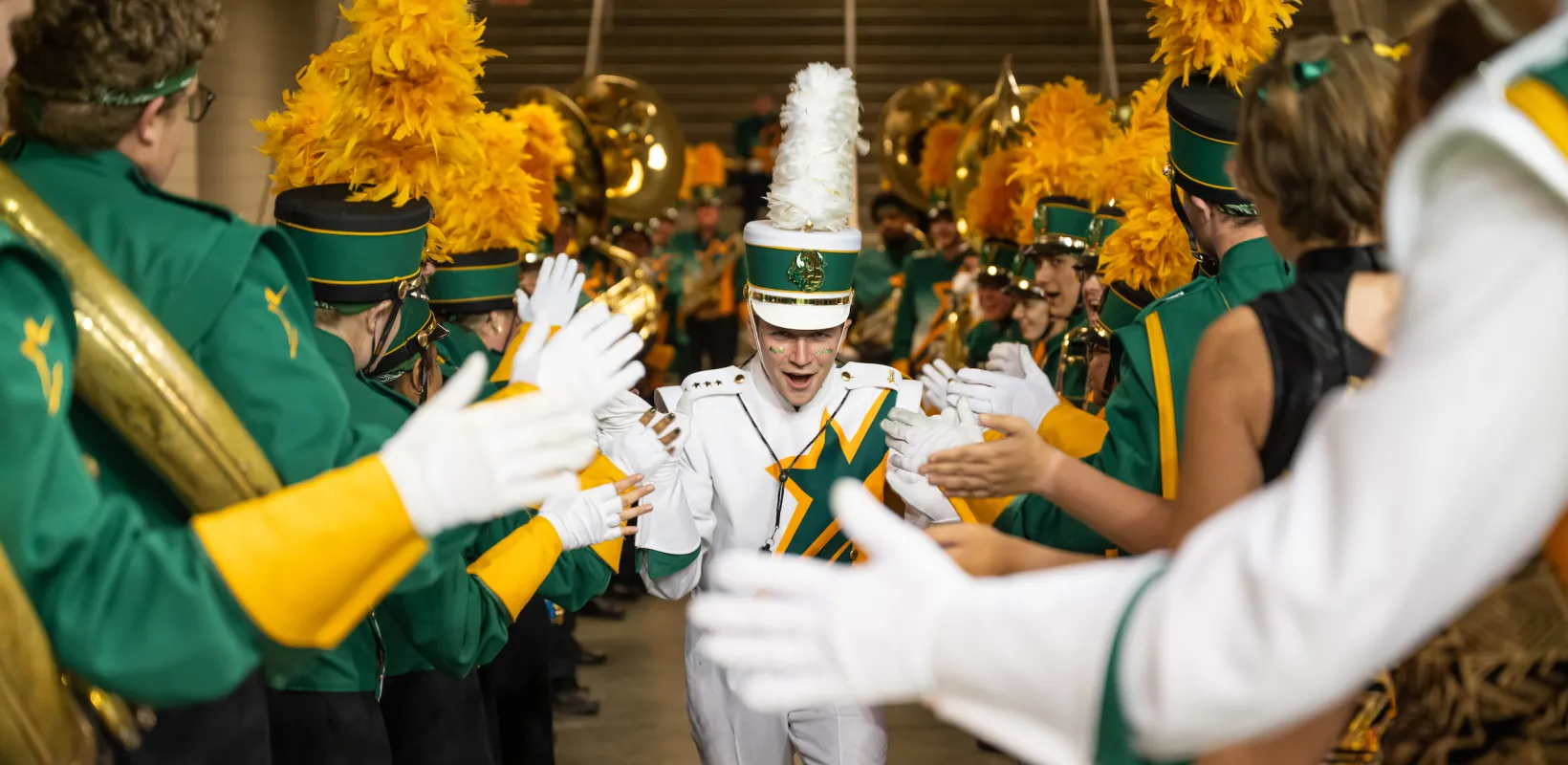 Gold Star Band member gets high fives from other band members before the Homecoming football game