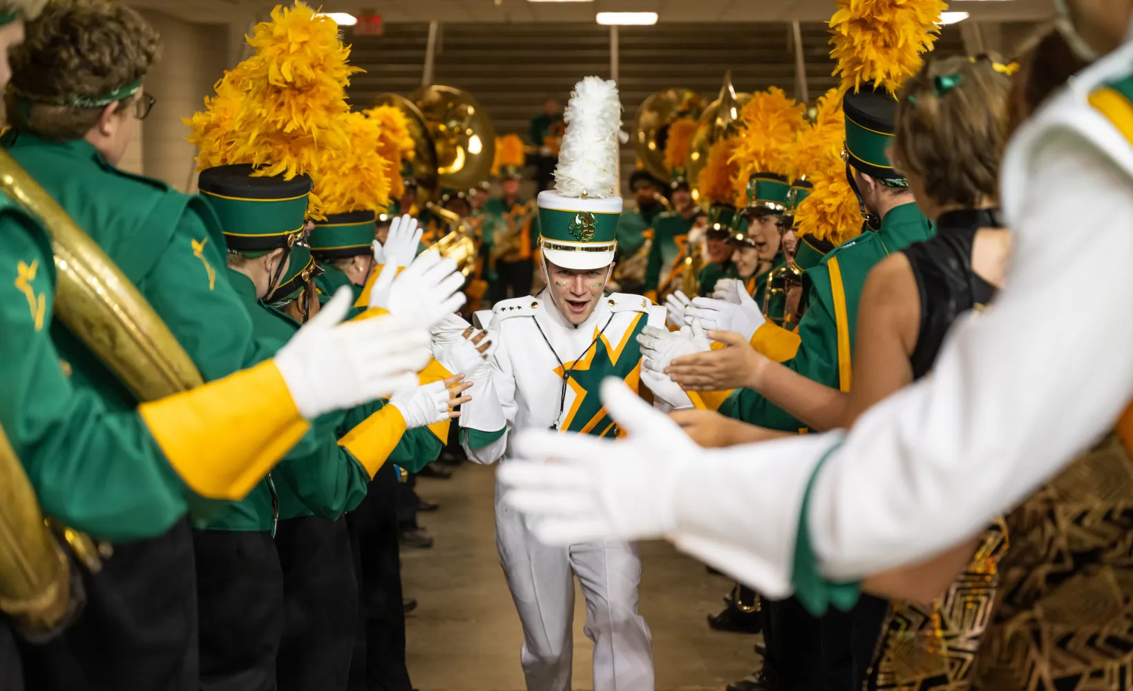 Gold Star Band member gets high fives from other band members before the Homecoming football game