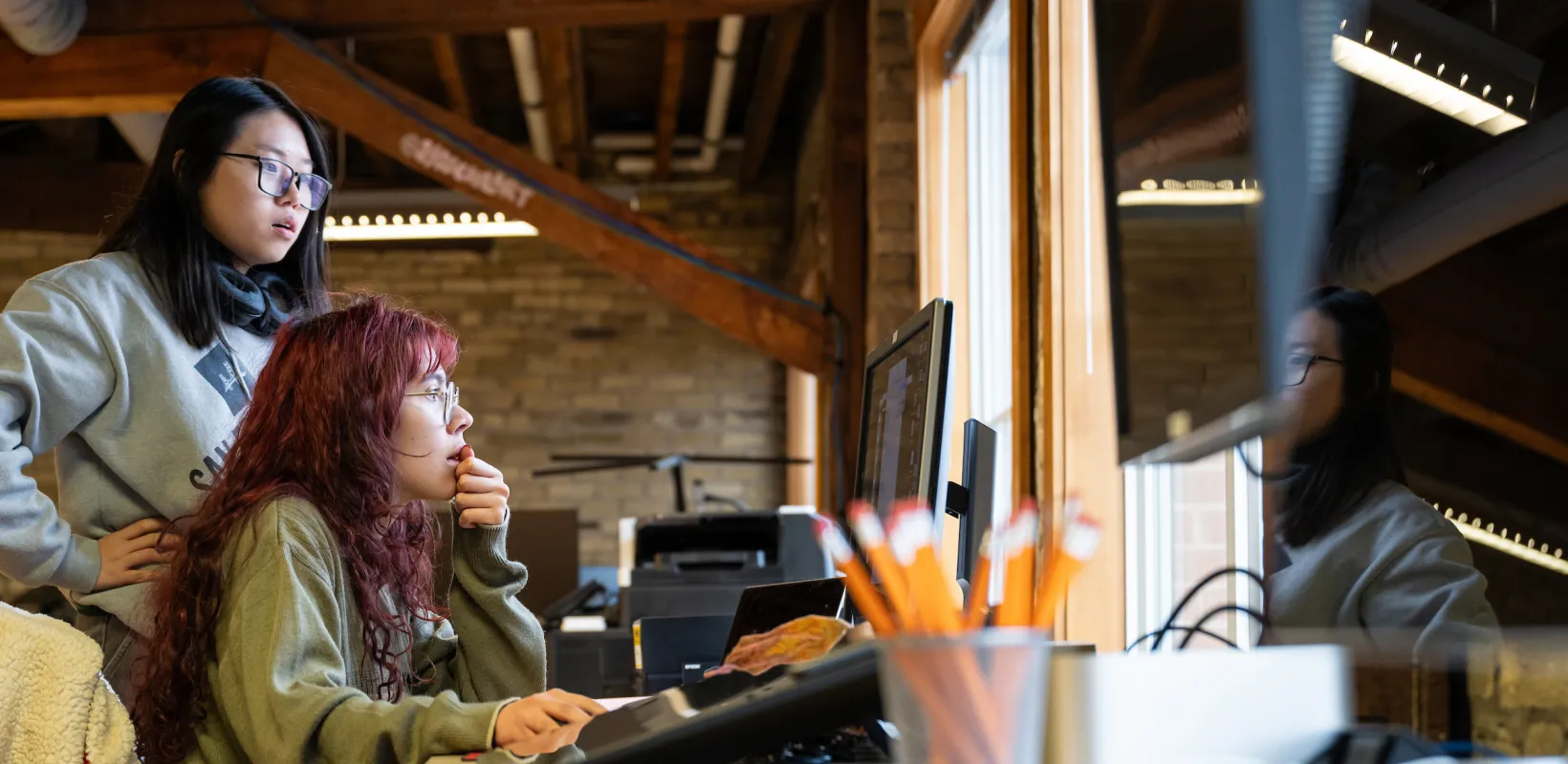 students collaborating around a computer in a graphic design studio