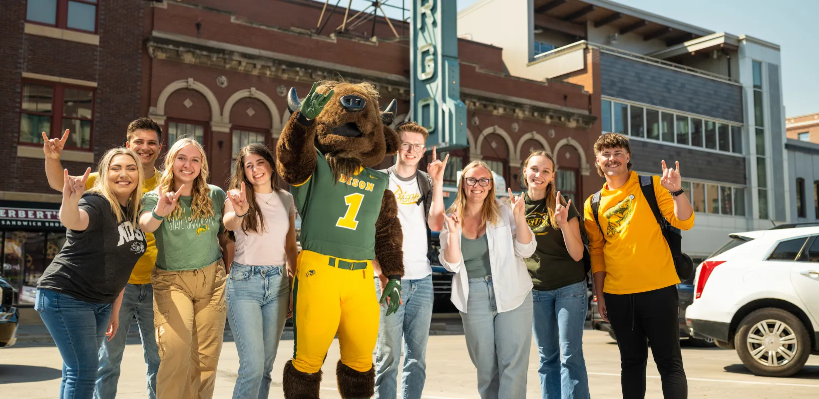 group of students posing with Thundar downtown in front of the Fargo sign
