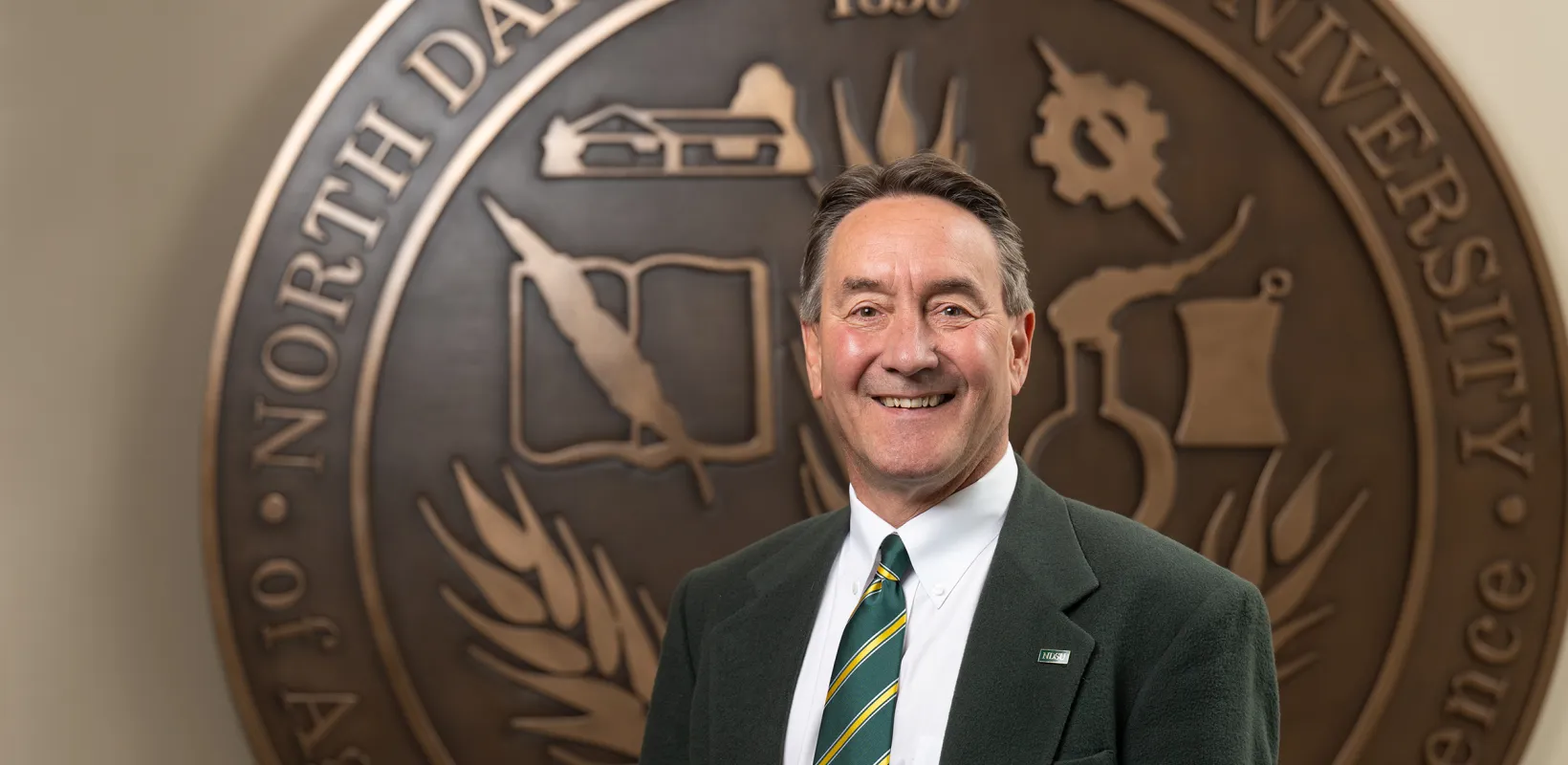 Rick Berg stands in front of the NDSU seal at Old Main