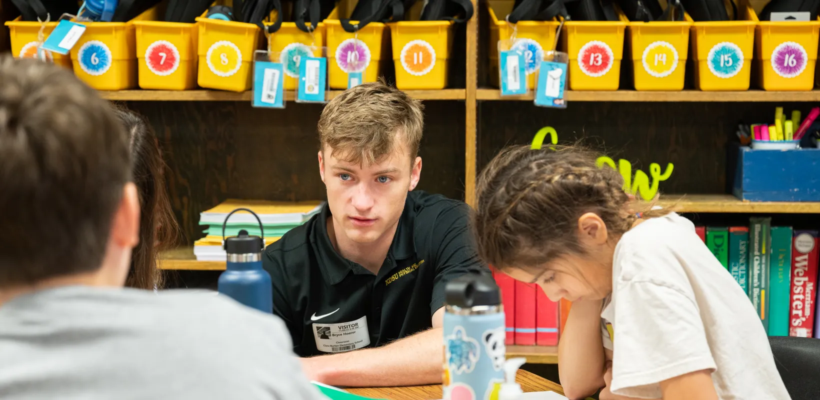 Student teacher working with students at desks. 