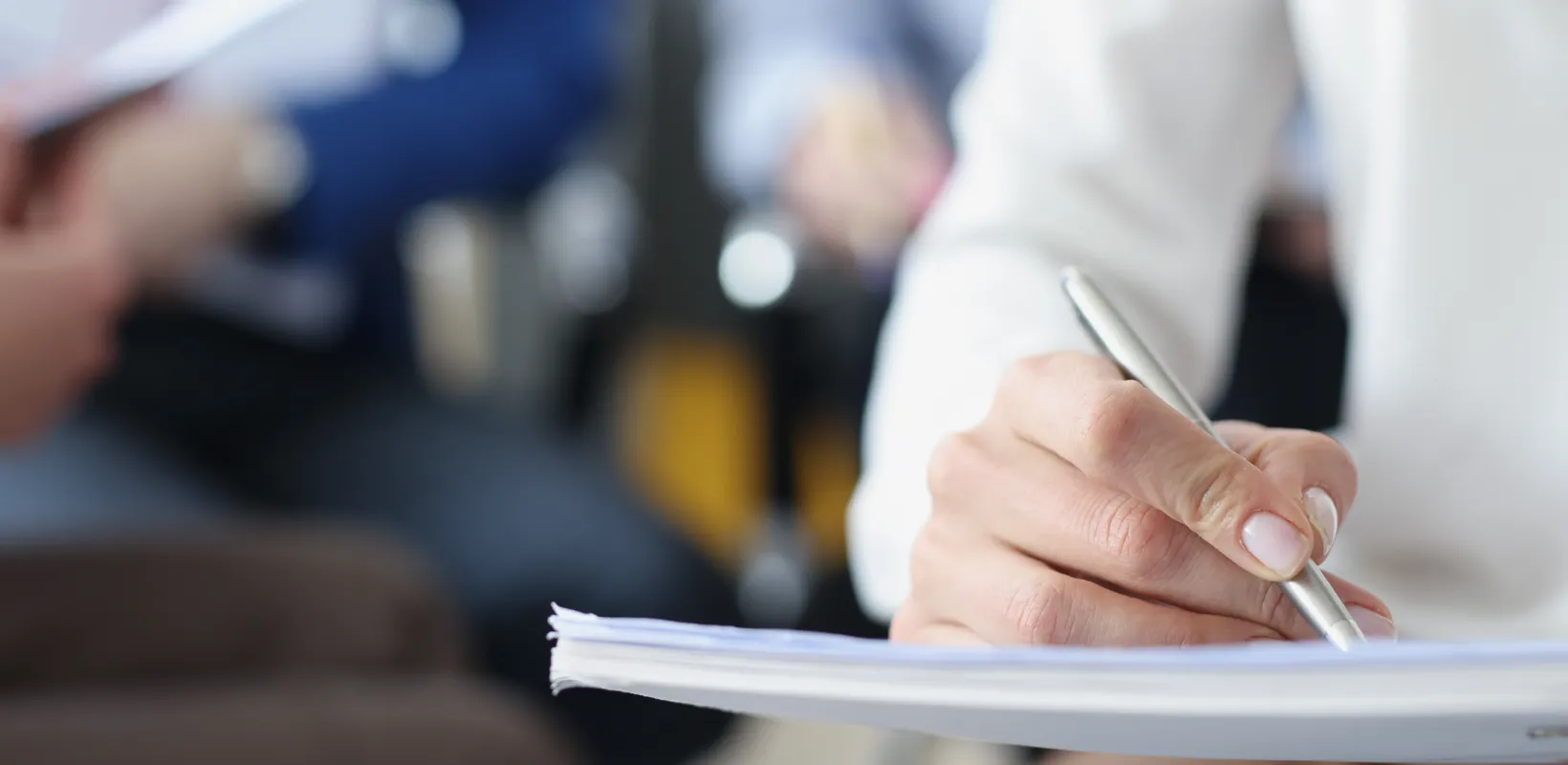 A person writing notes in a book at a training session