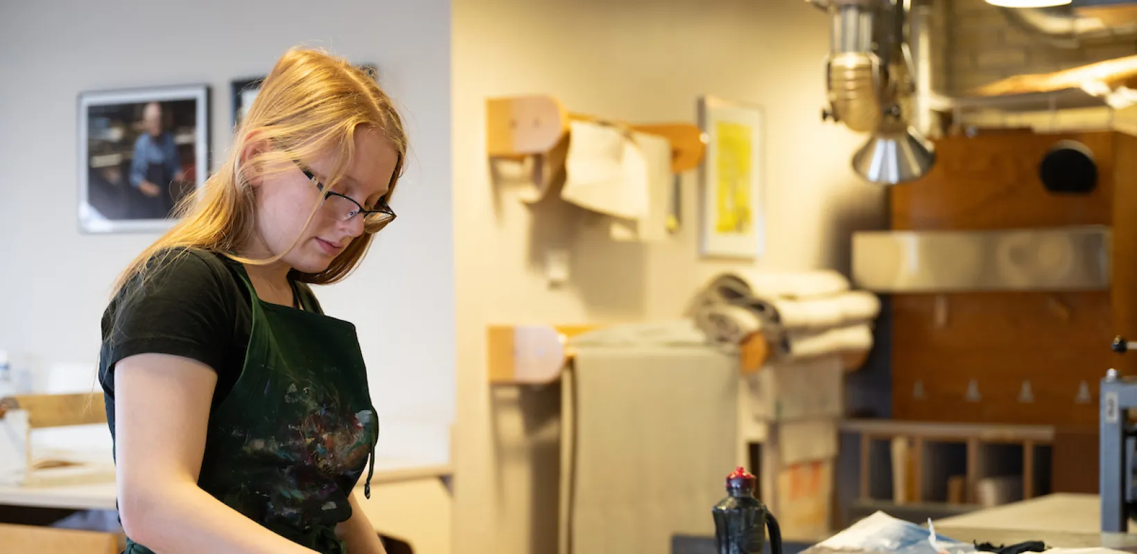 Student working in design studio wearing a black apron and black gloves.
