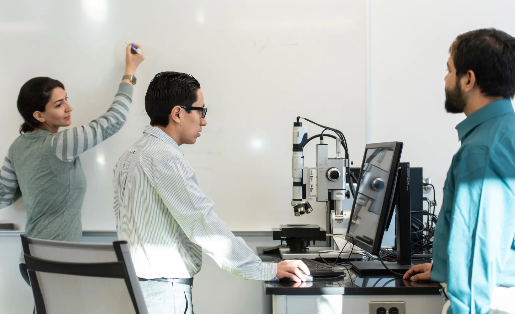 graduate engineering students work together at the whiteboard and computer