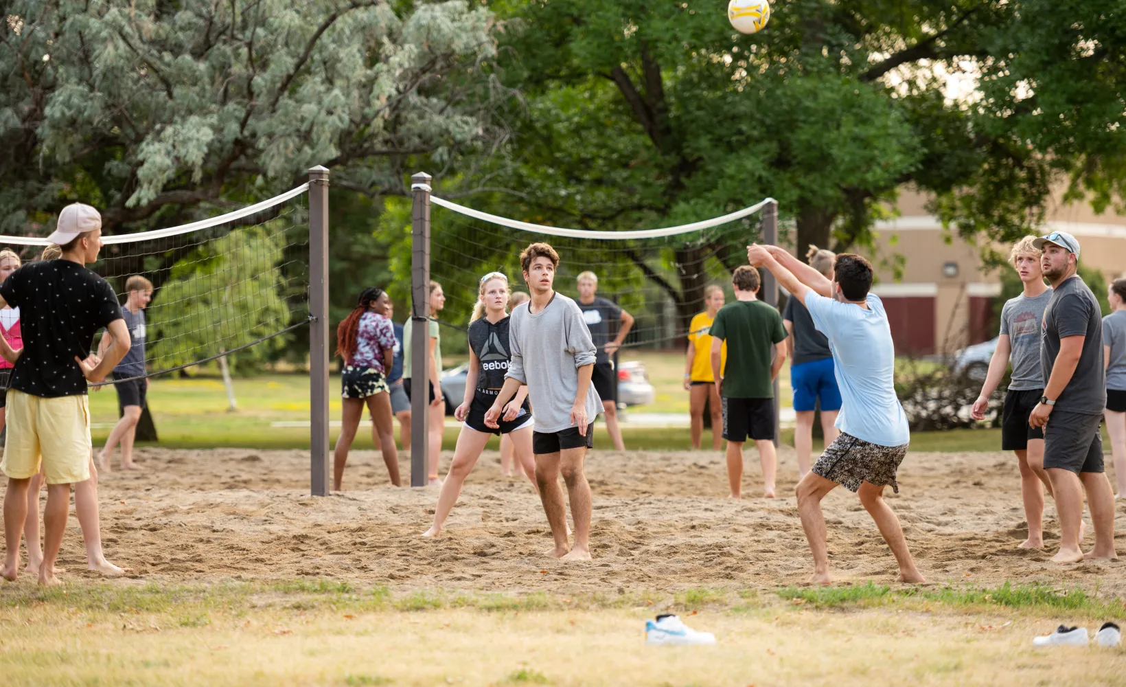Group of students playing sand volleyball outside of the halls