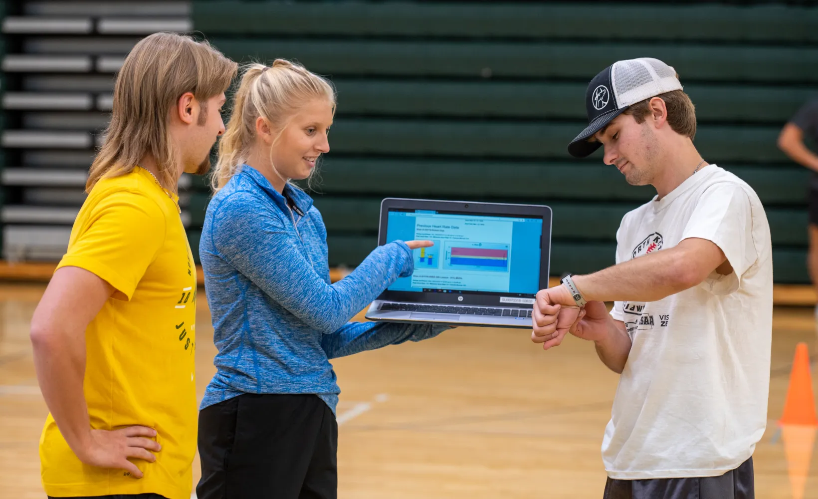 Students working with a laptop in gym.