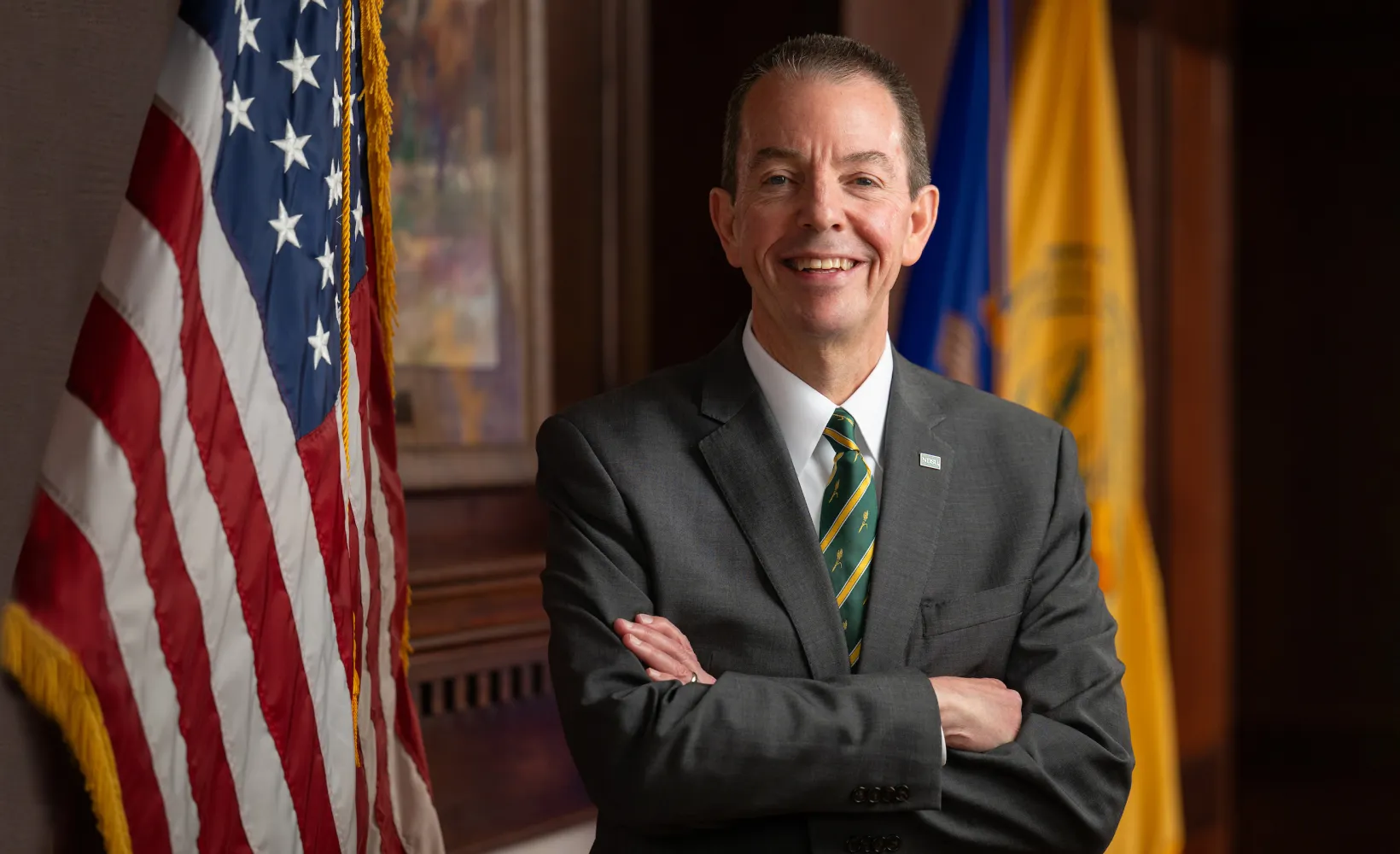 NDSU President Stewart in front of NDSU, N.D. and U.S. flags