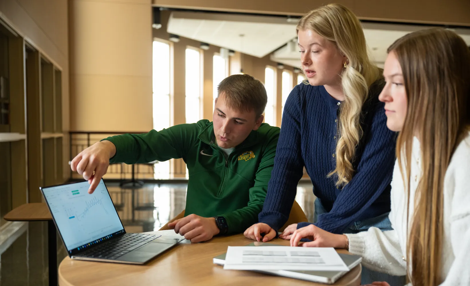 students gather around laptop during class