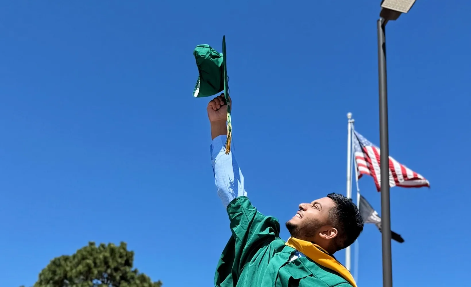 Student holding up grad cap to the sky