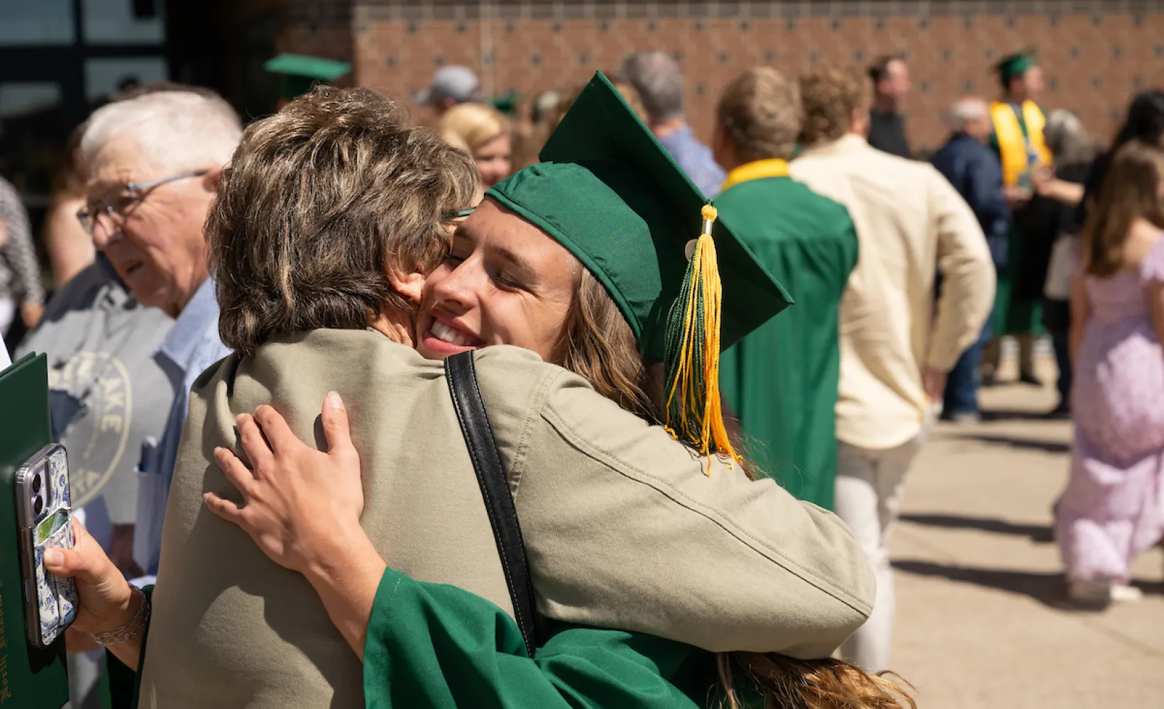 graduate hugs her family member at commencement