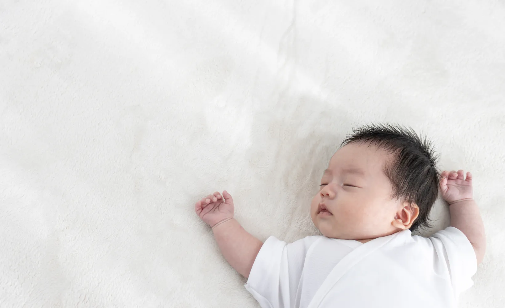 A sleeping baby lays on a white background.