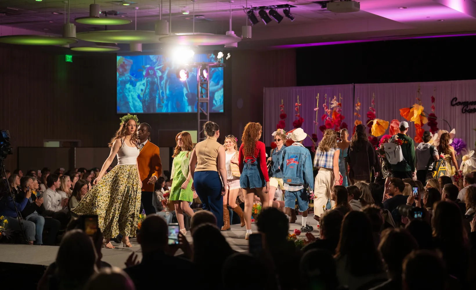 Models walking on stage wearing designed outfits.