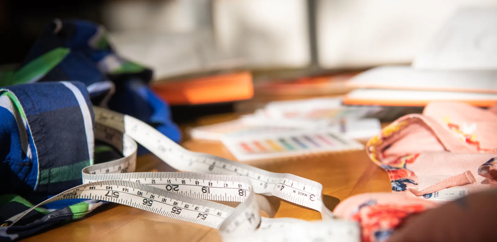 Measuring tap laying on table along with material and other items.