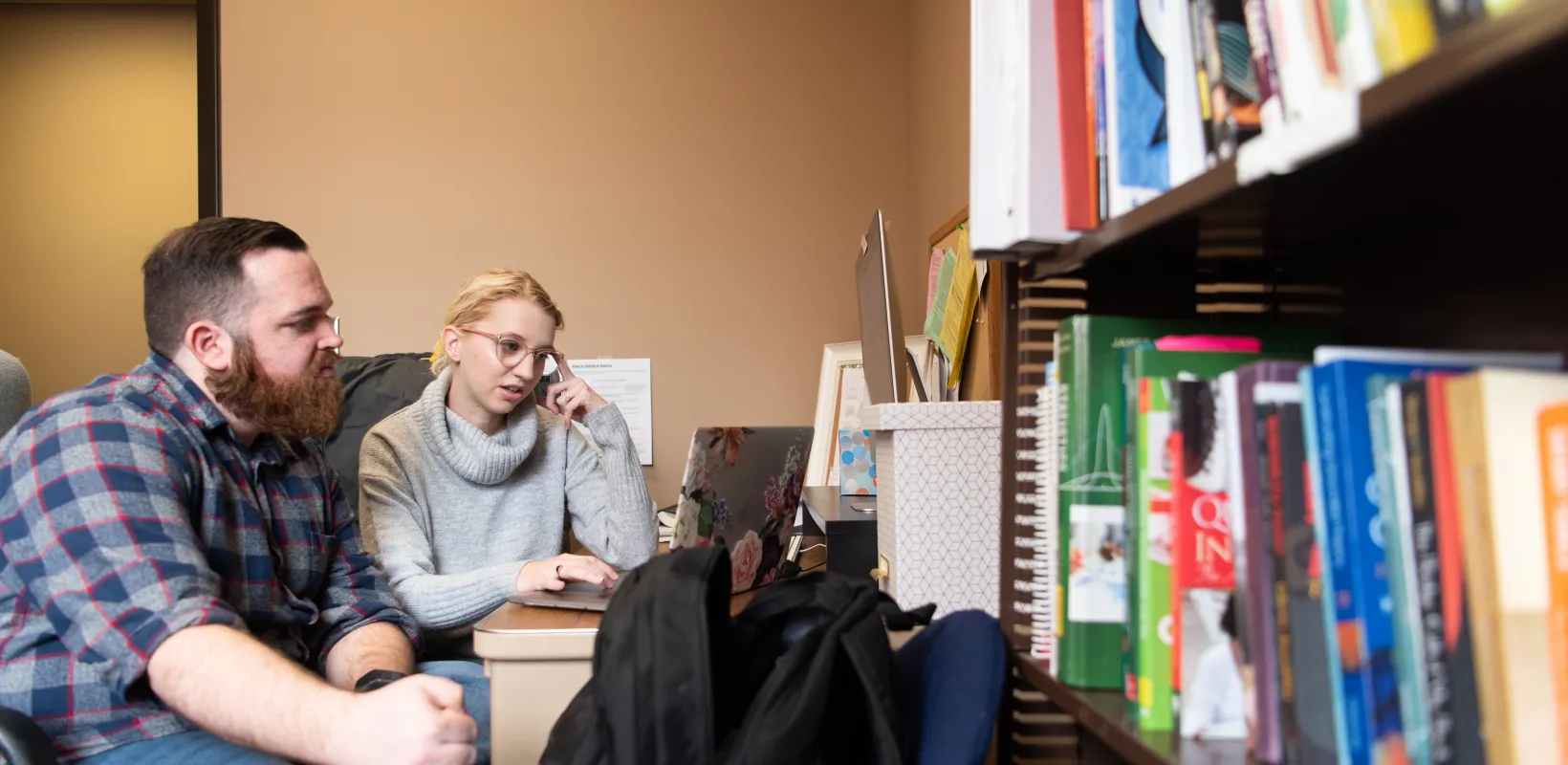 Students working together on a laptop. One student typing while another looks on intently.