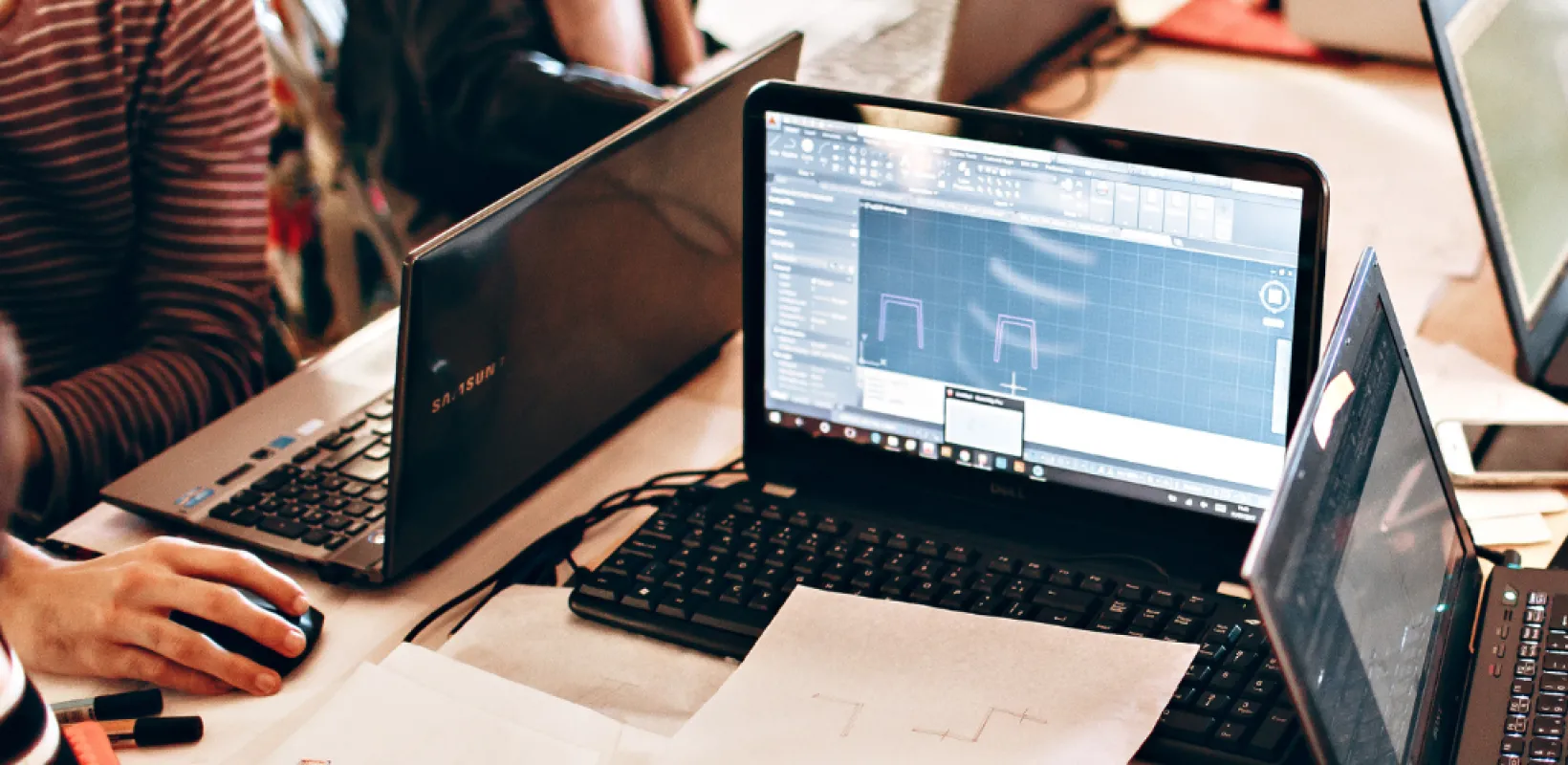 Four Laptops and a cell phone around a table 