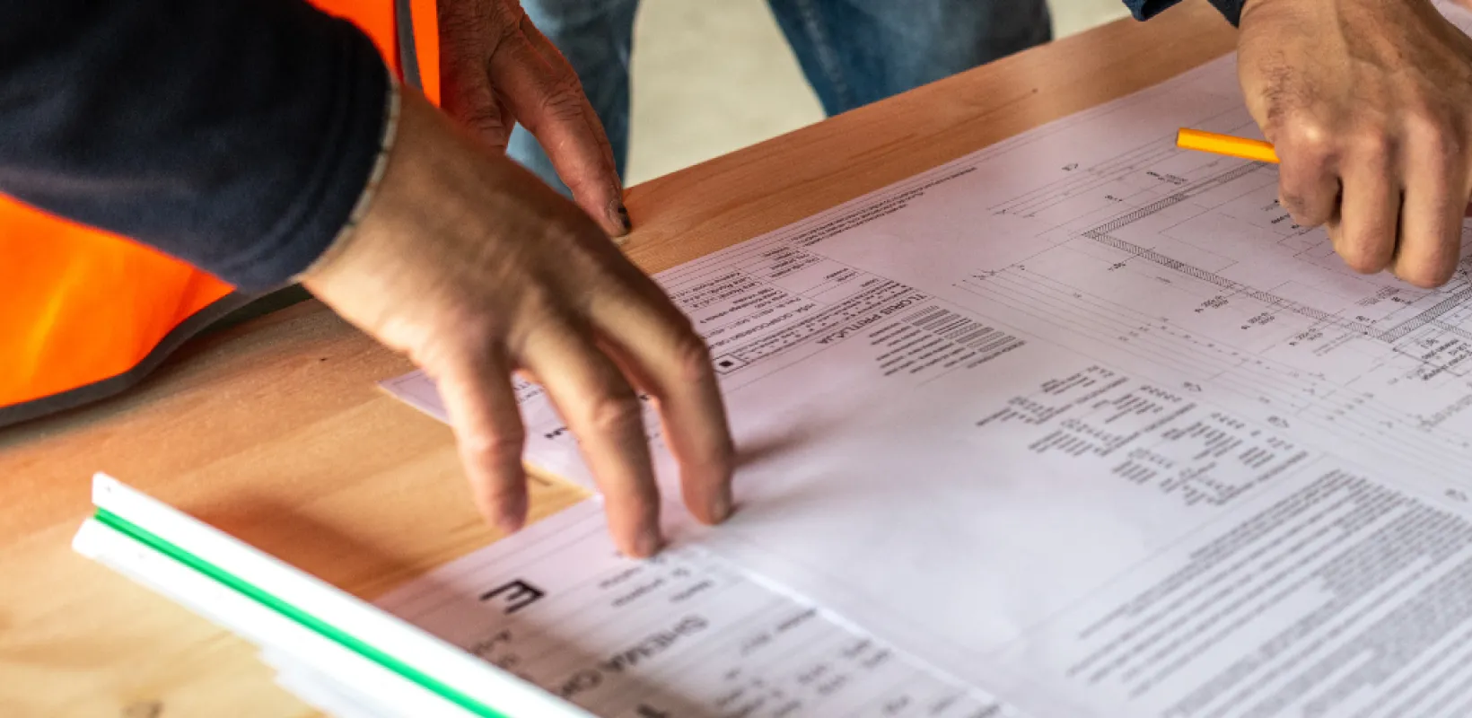Hands referring and pointing to different parts of a construction summary sheet