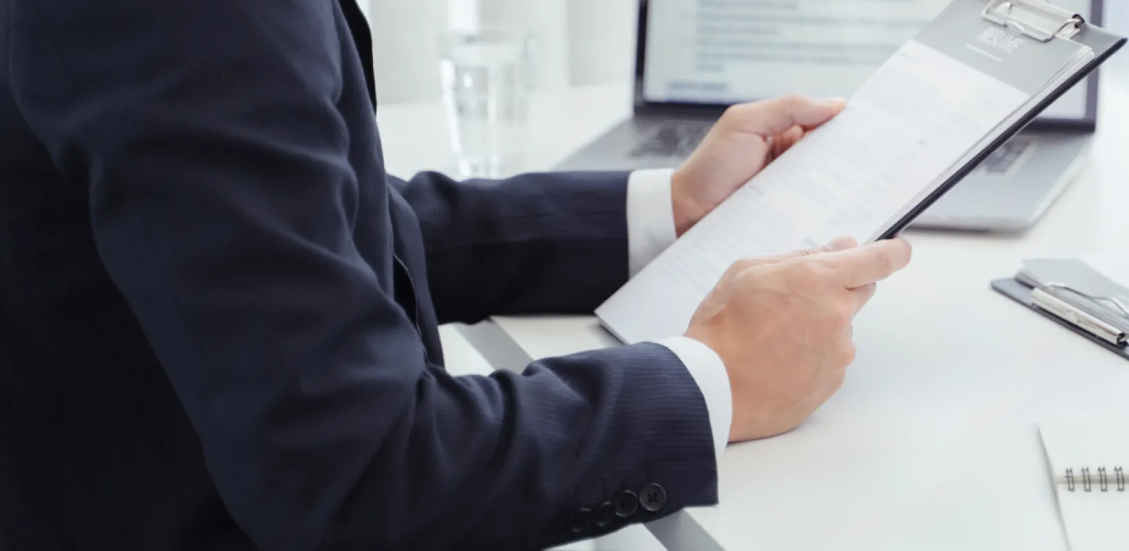 professional reviewing a resume on a clipboard while interviewing a prospective employee