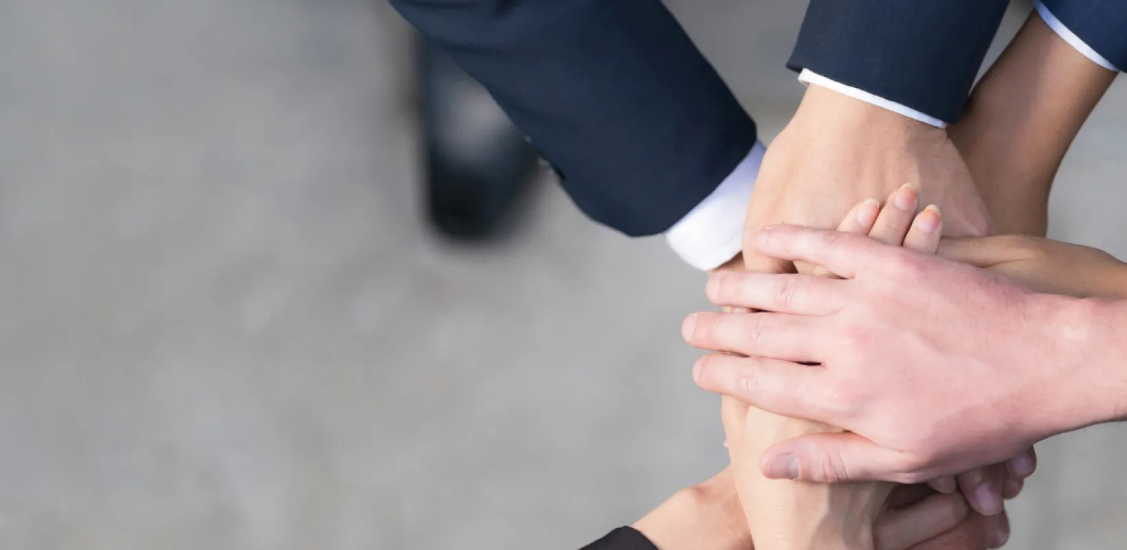 multiple business professionals with hands on top of one another together