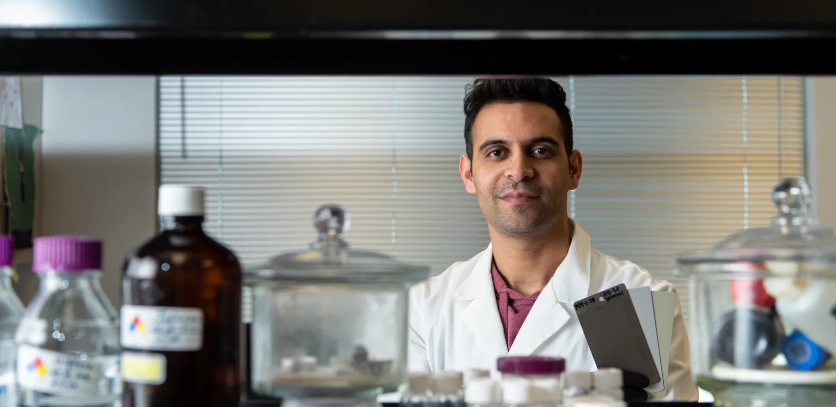 Research student looking confidently at camera sitting in a lab setting. 