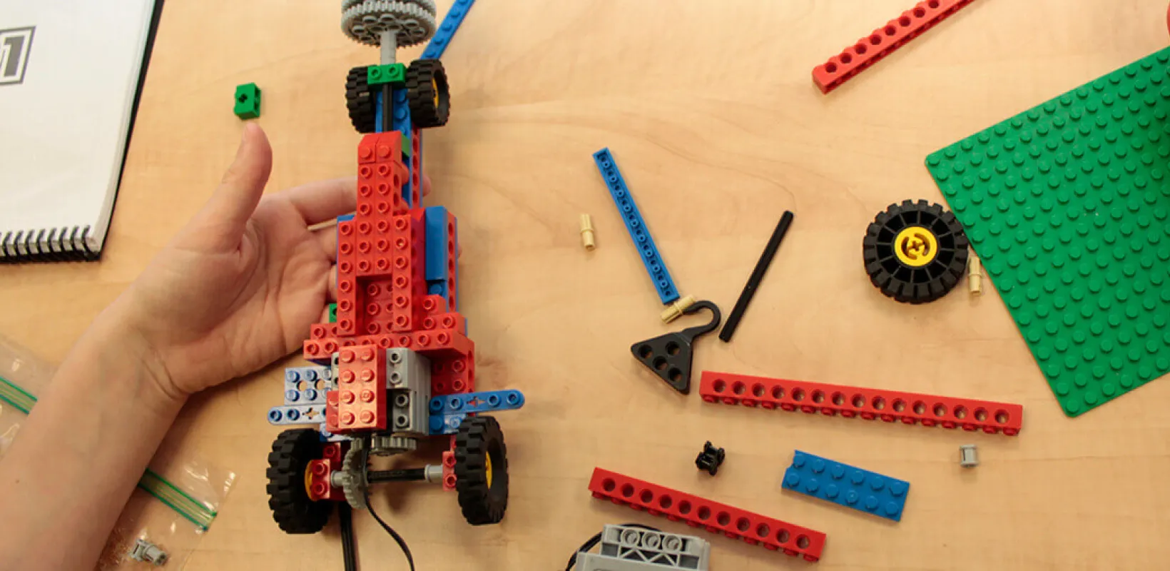 Child's hand building a lego car