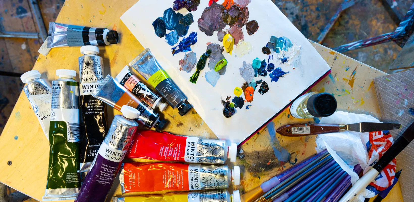 Art supplies on table including paint and paint brushes.