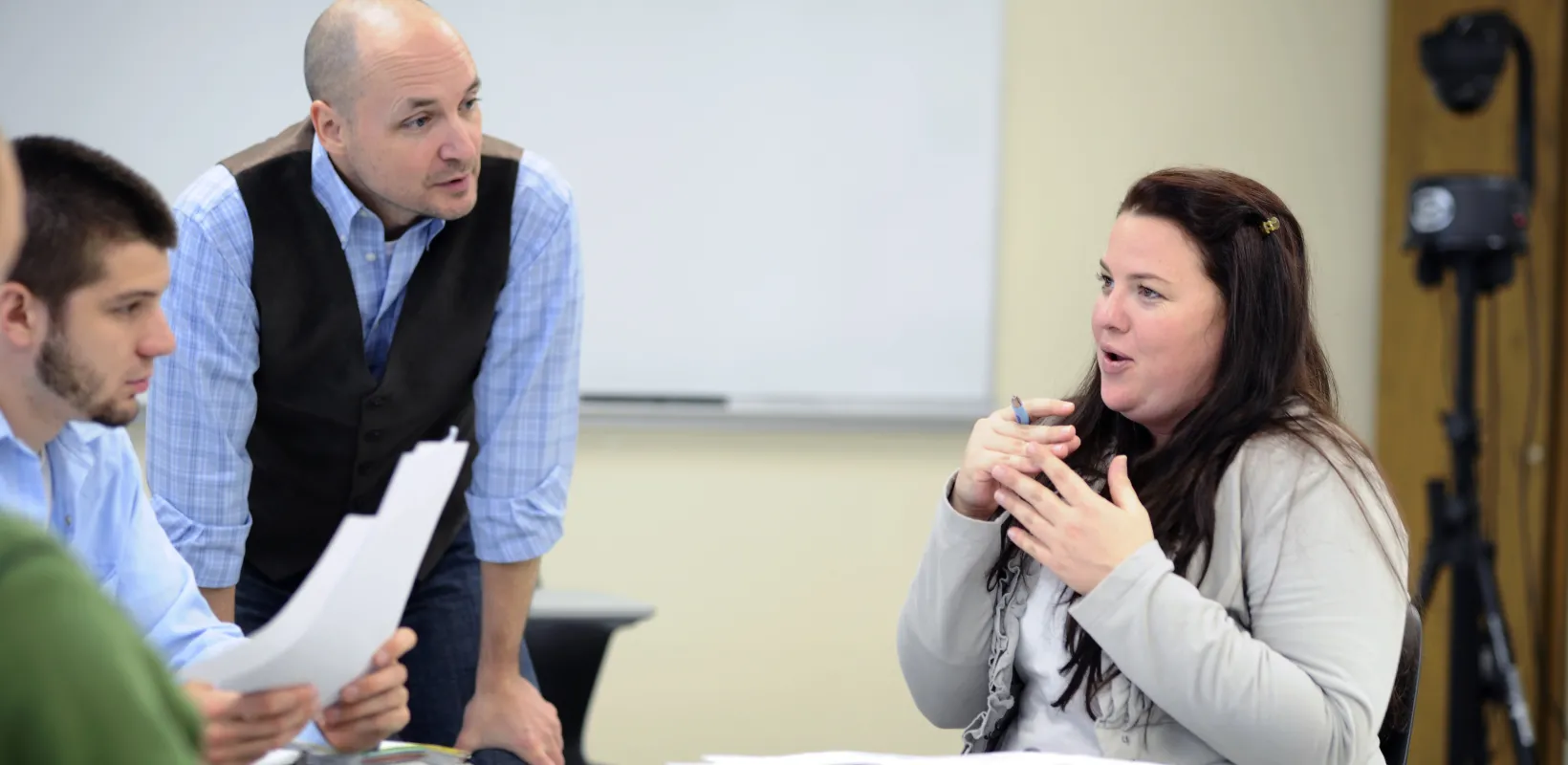 Students and professor talking in a classroom setting. 