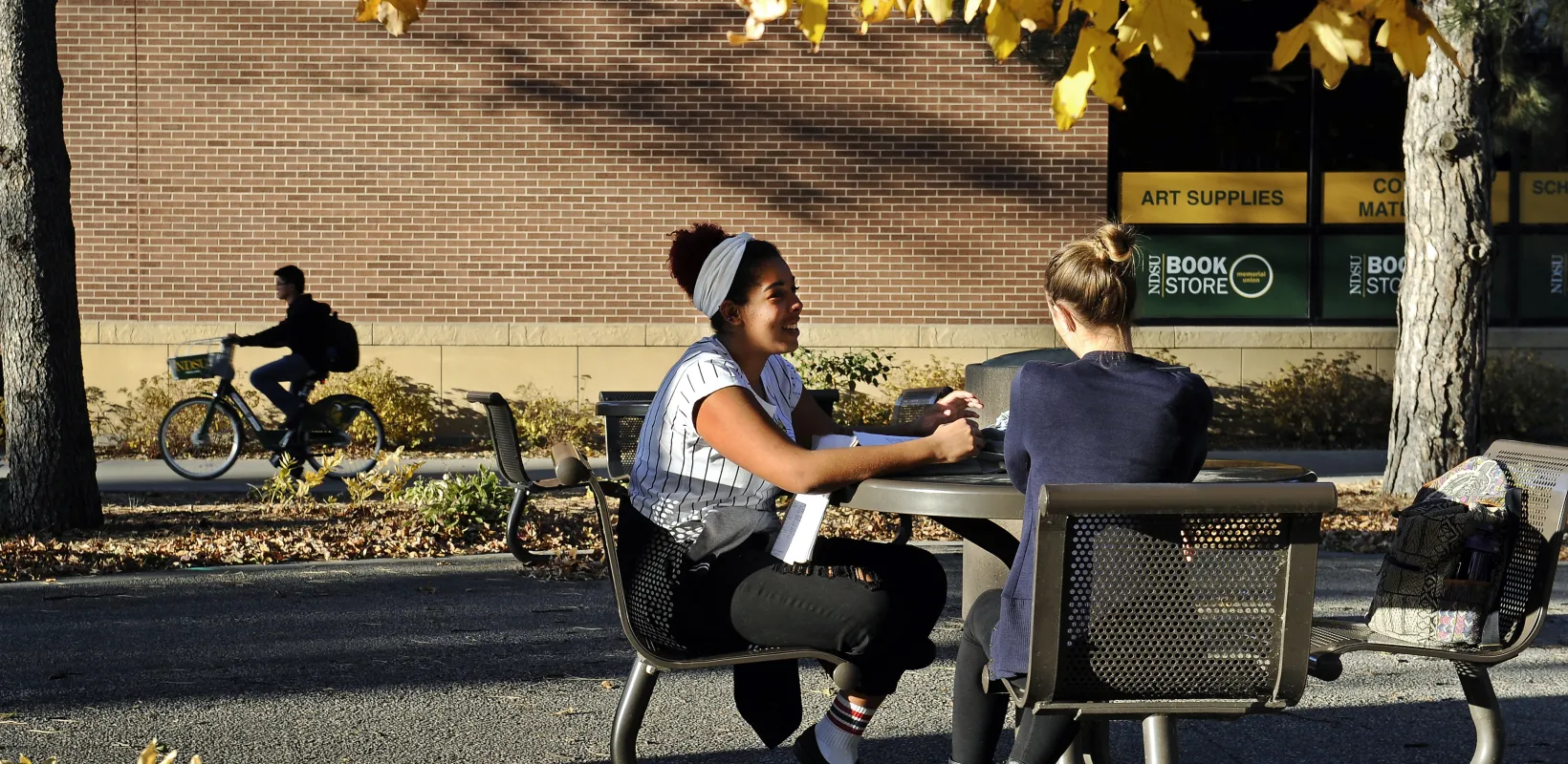 Students stilling at table outside on a fall day.