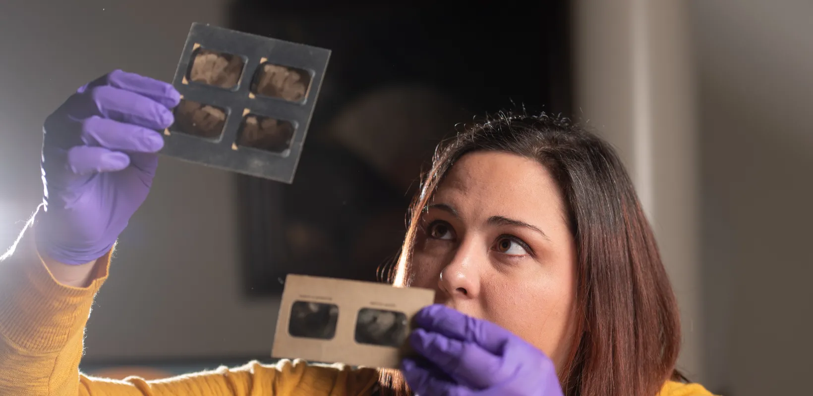 Student wearing a yellow sweater working with film archives.