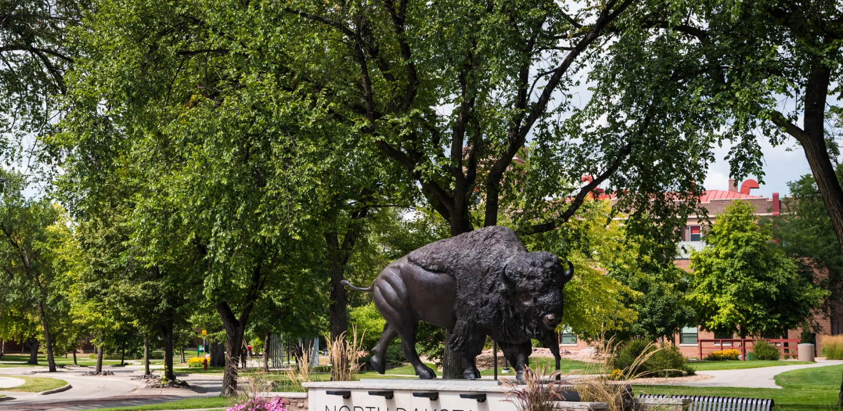 Bronze Bison statue with green trees in the background.