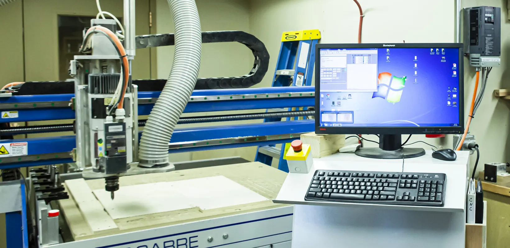 Machine and computer located in woodshop.