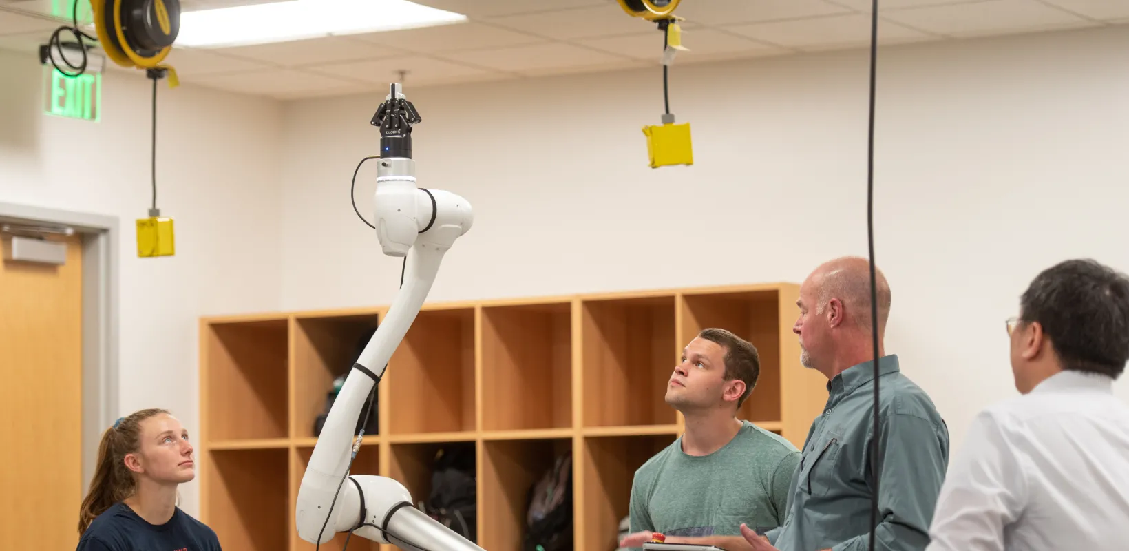 Dr. Alan Kallmeyer operating robot arm with students