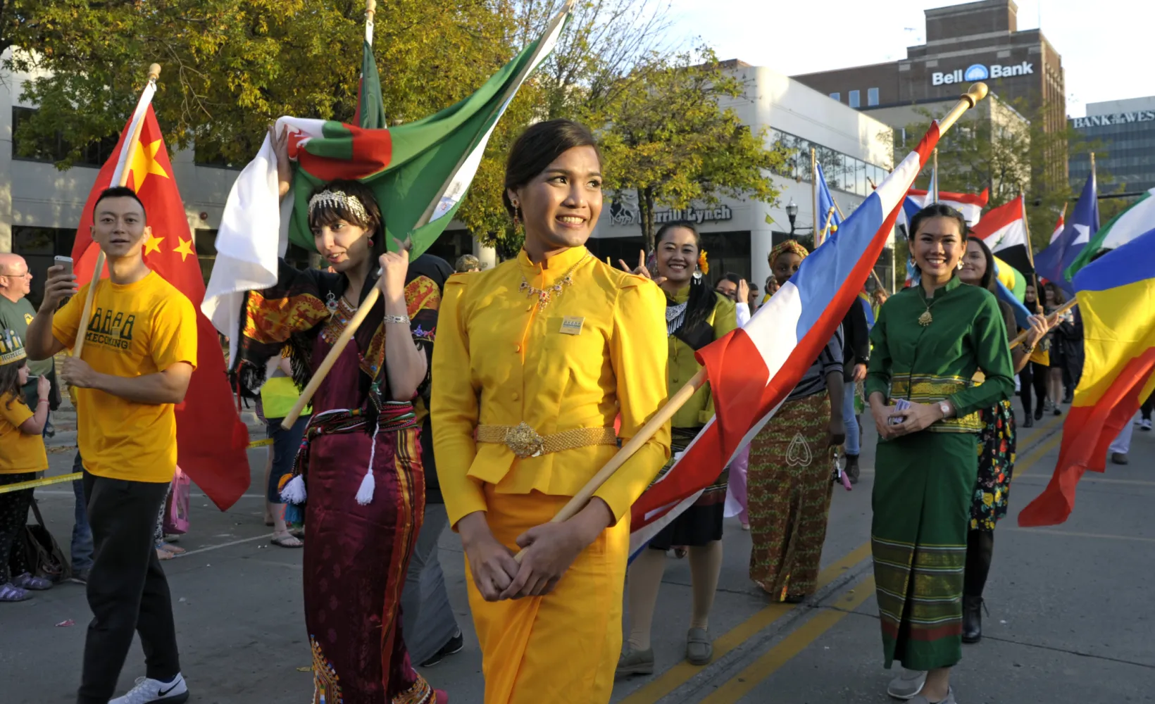 Students carrying flags and walking in a parade in downtown Fargo.
