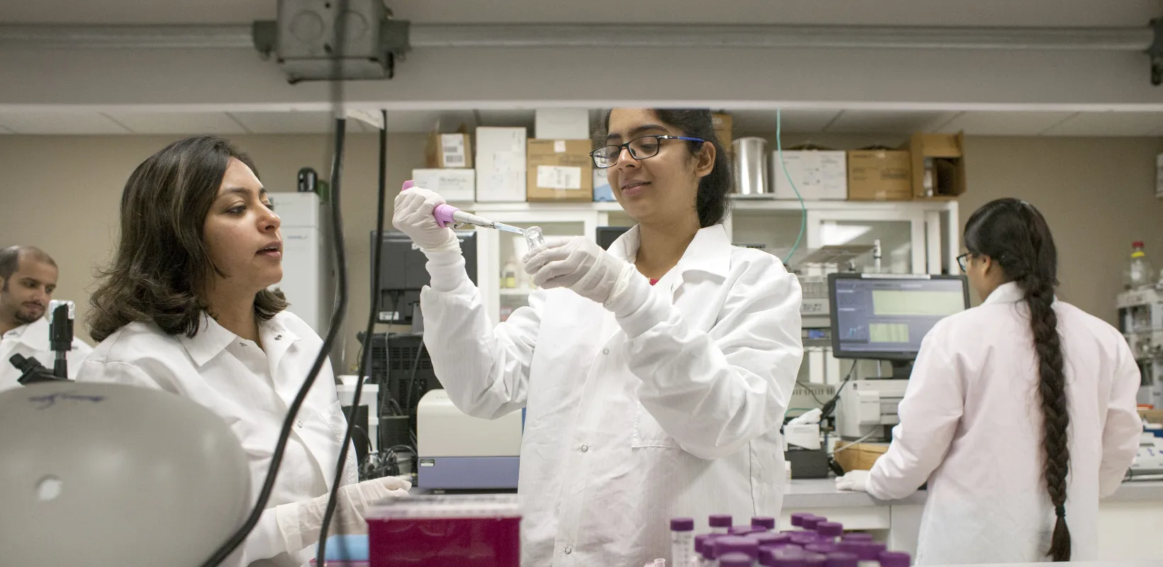 Students in a lab with one using a pipet