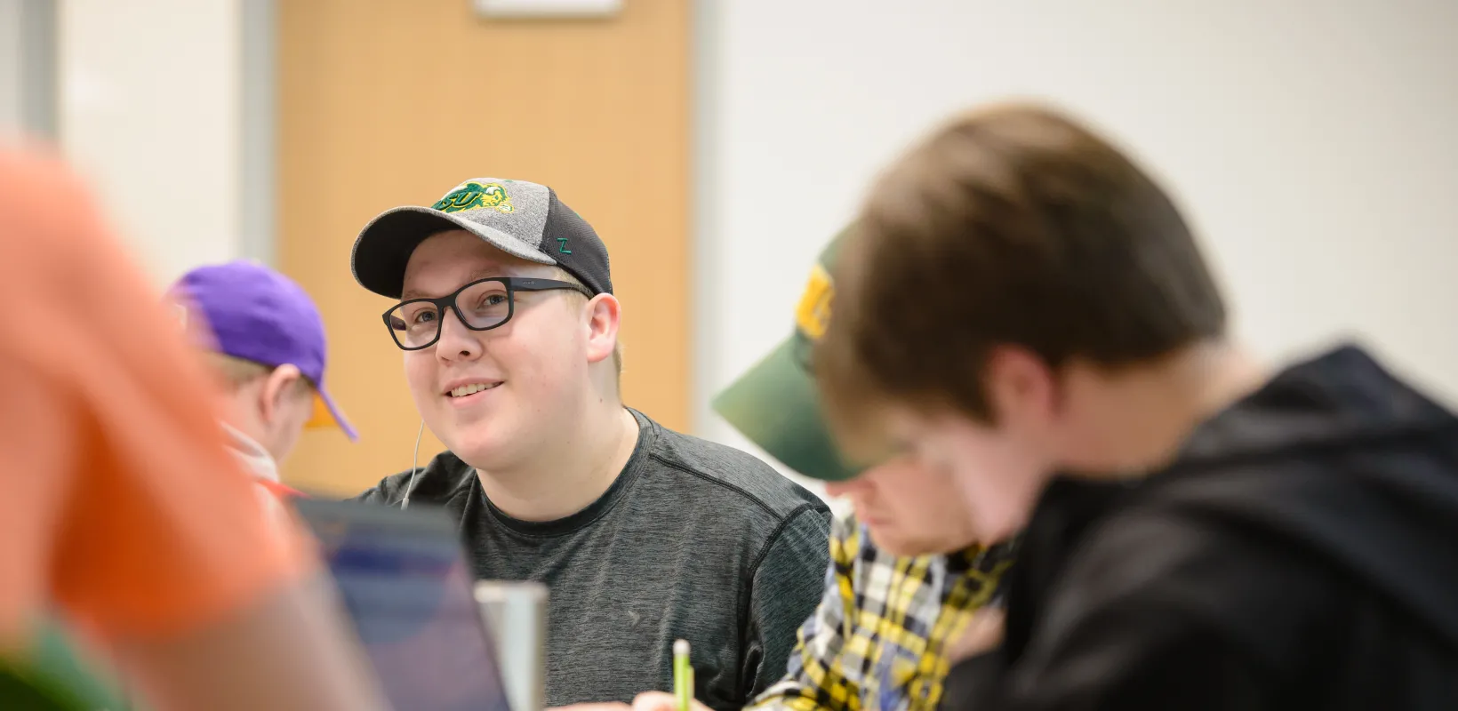 Student sitting at desk looking at front of classroom.