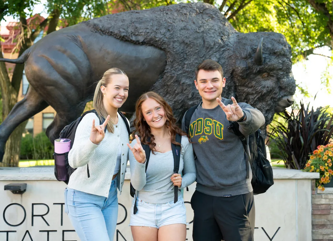 students give horns up in front of the Bison statue during Welcome Week