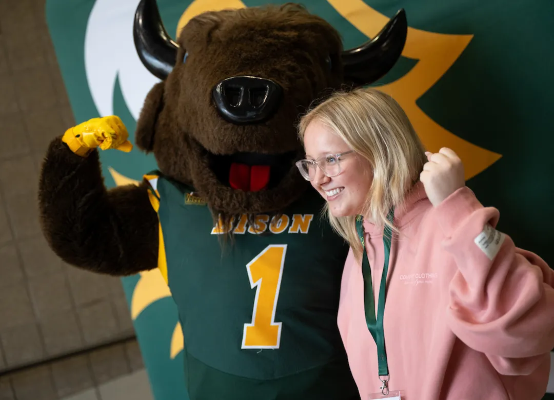 student poses with Thundar during a Discover NDSU event