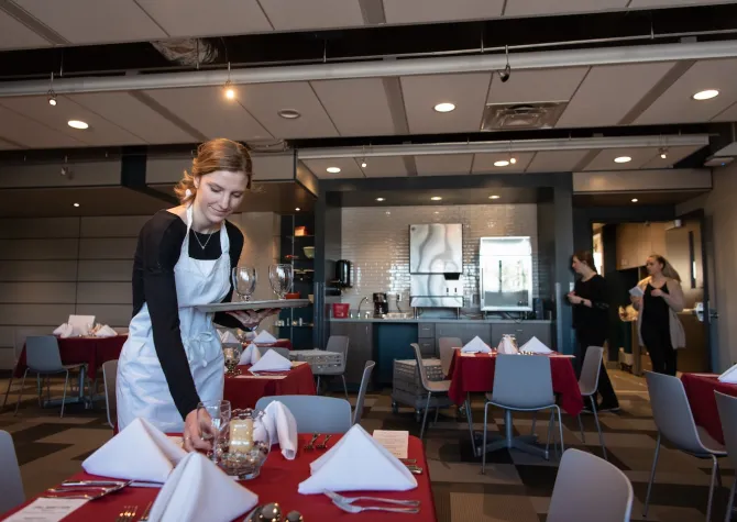 an NDSU student sets a table at 800 Café