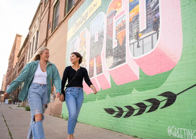 students walking past Fargo mural in downtown Fargo