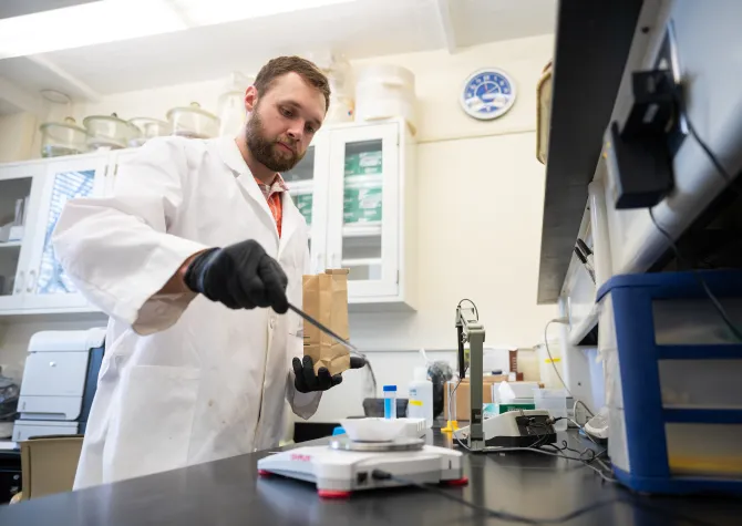 student weighing samples of dirt on a scale