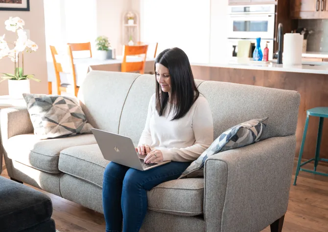 online student working on laptop from living room couch