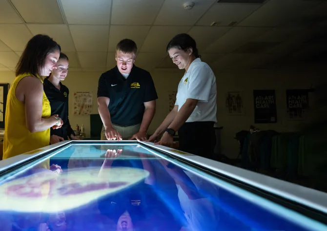 students and a professor looking at a diagram on a table