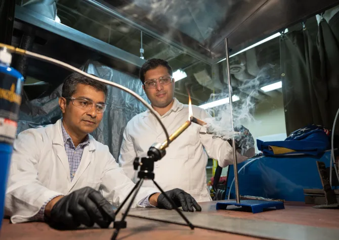Scientists working in the lab. Both wearing lab coats, eye protection and gloves. 