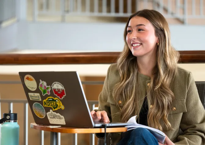 Student sitting with laptop open, smiling