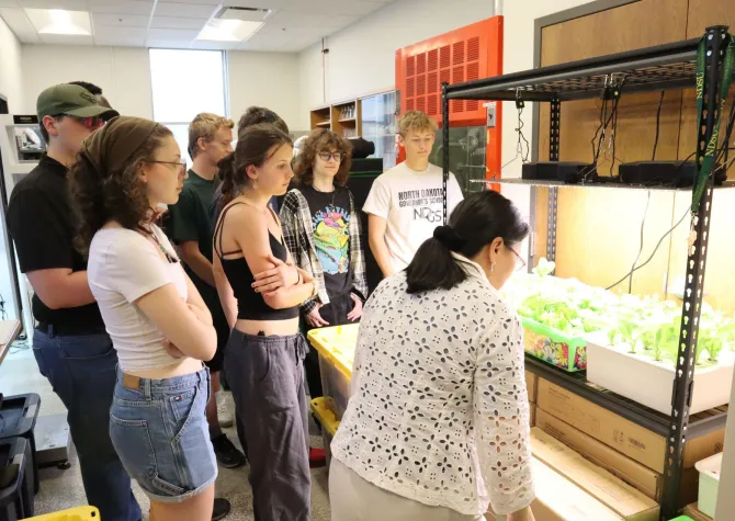 Professor Xinhua Jia shows an experimental crop of plants to a group students