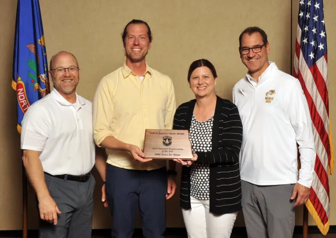 A man and woman hold a plaque next to two men smiling