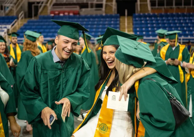 NDSU graduates laughing and celebrating at the end of their commencement ceremony