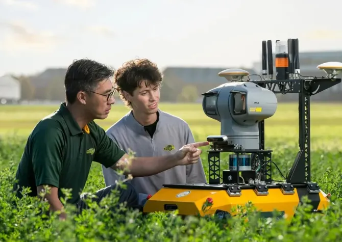 Professor and student in field with robot