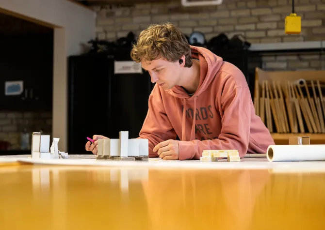 Architecture student working on design models on top of a worktable. 
